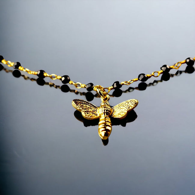 Elegantes Armband mit Onyxrondellen und goldenem Bienenanhänger