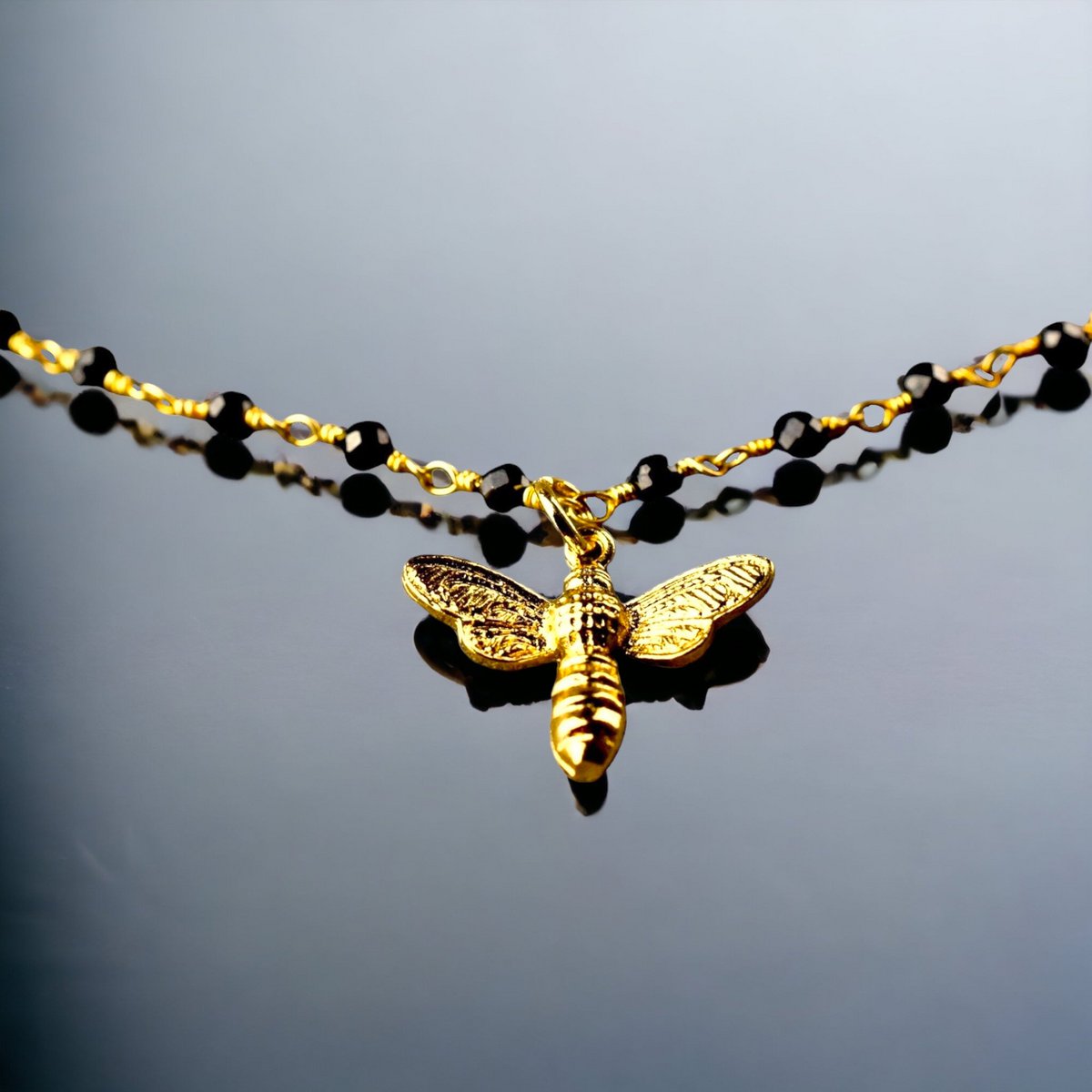 Elegantes Armband mit Onyxrondellen und goldenem Bienenanhänger