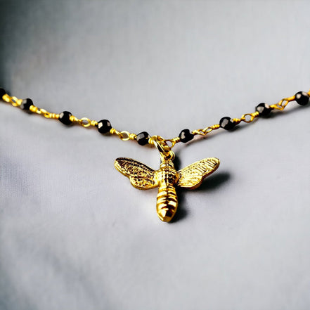 Elegantes Armband mit Onyxrondellen und goldenem Bienenanhänger