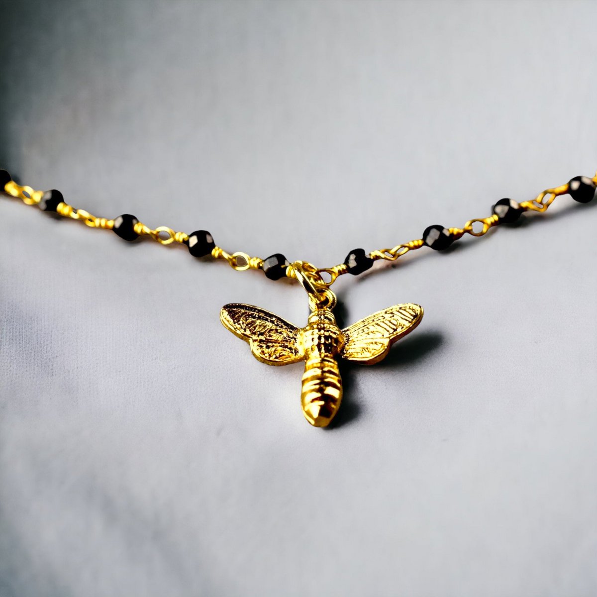 Elegantes Armband mit Onyxrondellen und goldenem Bienenanhänger