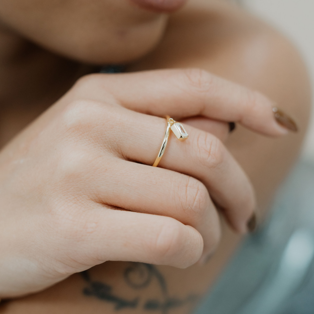 vergoldeter Ring mit baumelnden Zirkoniastein im Baguetteschliff, der am Ring befestigt ist