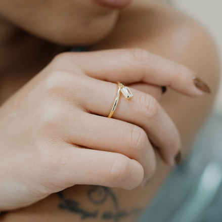 vergoldeter Ring mit baumelnden Zirkoniastein im Baguetteschliff, der am Ring befestigt ist