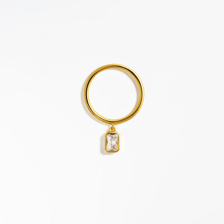 vergoldeter Ring mit baumelnden Zirkoniastein im Baguetteschliff, der am Ring befestigt ist