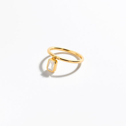 vergoldeter Ring mit baumelnden Zirkoniastein im Baguetteschliff, der am Ring befestigt ist