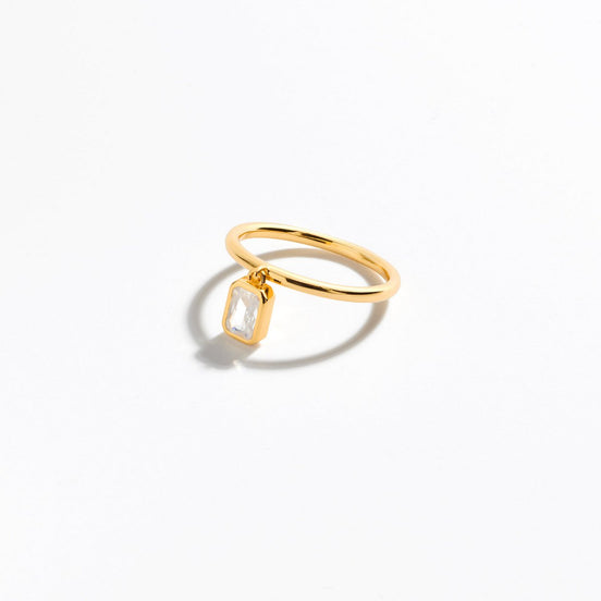vergoldeter Ring mit baumelnden Zirkoniastein im Baguetteschliff, der am Ring befestigt ist