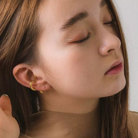 Minimalistischer Gold Ear Cuff getragen, zeigt das unisex Design des ohraufsitzenden Schmuckstücks aus 18K vergoldetem Messing.