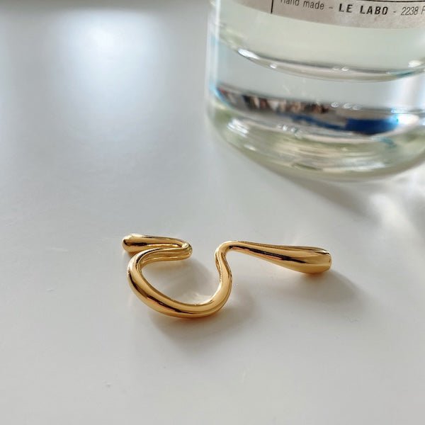 Nahaufnahme des geschwungenen Floating Ear Cuff aus Messing mit 18K Vergoldung, hebt die fließende Form hervor.